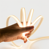 Hand holding a glowing, flexible light strip against a neutral background