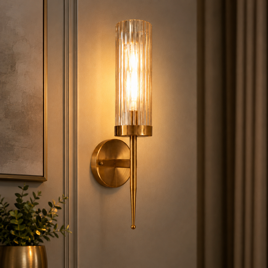 Gold wall sconce with glass shade on a neutral wall.