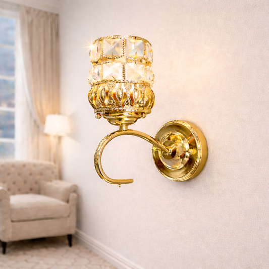 Gold wall sconce with crystal design on a white wall, next to a window and chair.