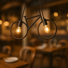 Bicycle-shaped pendant light with glowing bulbs in a blurred restaurant setting