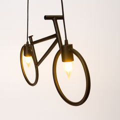 Bicycle-shaped pendant light with two lit bulbs on a white background