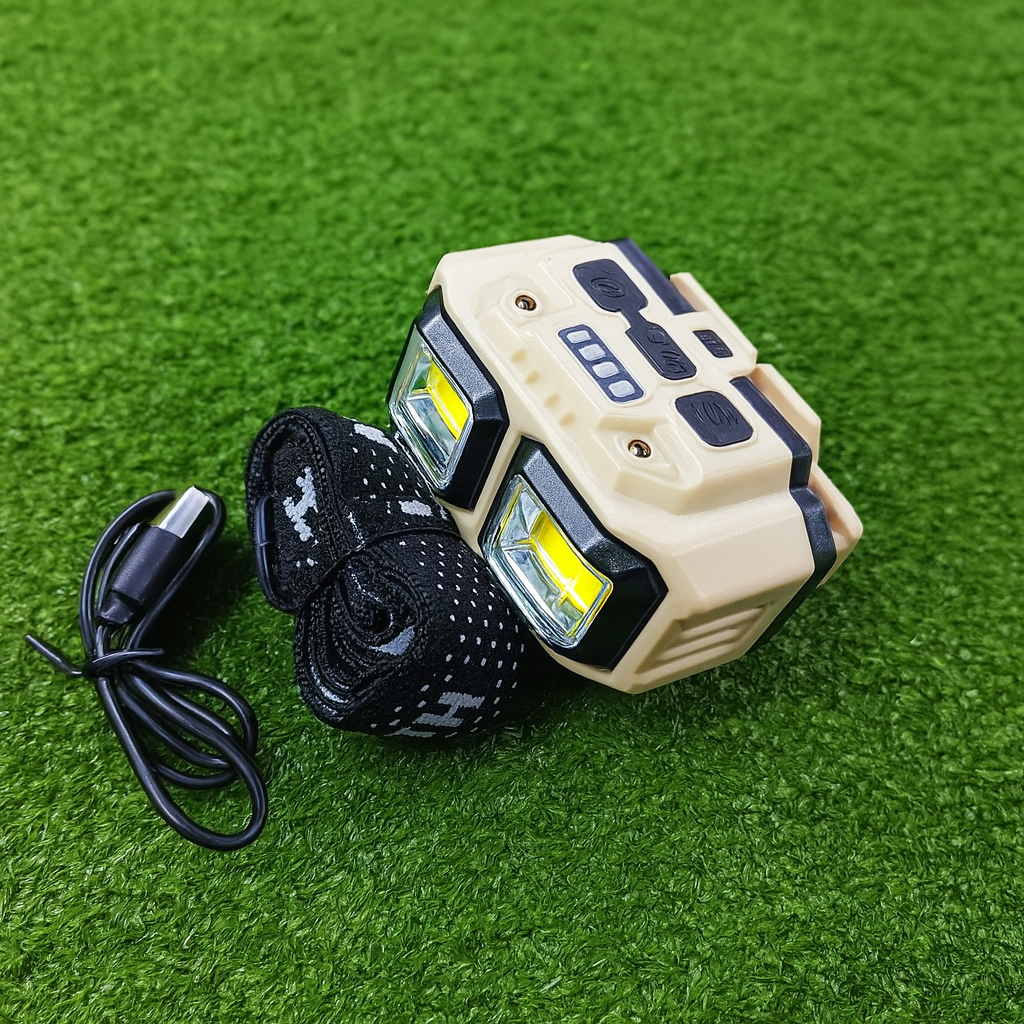 Rechargeable LED headlamp with strap and USB cable placed on green grass background