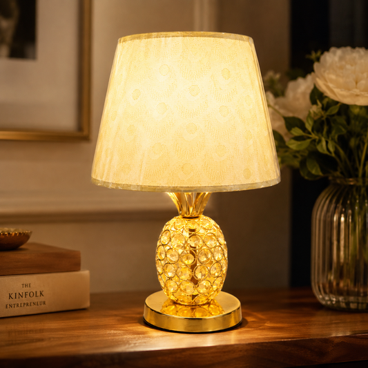 Decorative table lamp with a textured gold base on a wooden surface.