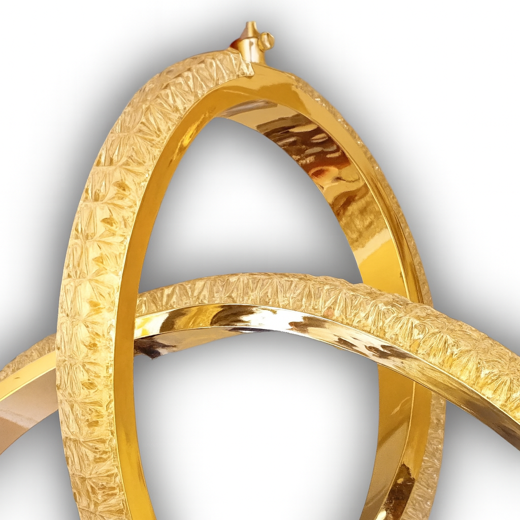 A close-up image of a luxurious gold chandelier featuring interlocking textured rings with a polished reflective finish. The design highlights intricate detailing and craftsmanship, set against a soft white background with a subtle natural shadow for a professional presentation