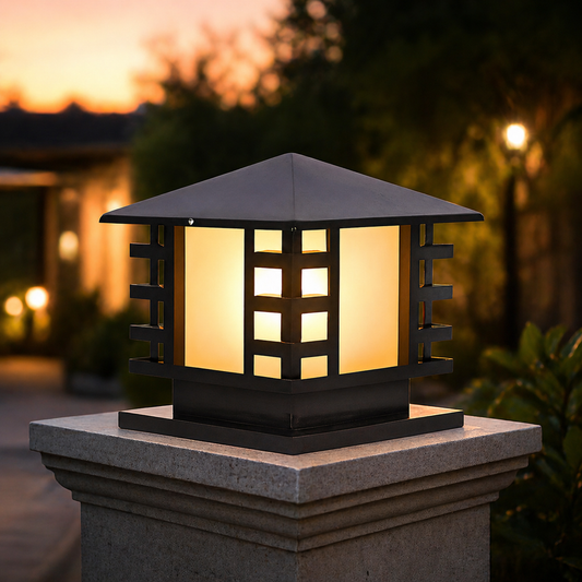 Decorative outdoor light fixture on a stone pedestal with a sunset background.