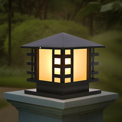 Black outdoor pillar light on stone gate post with warm LED glow