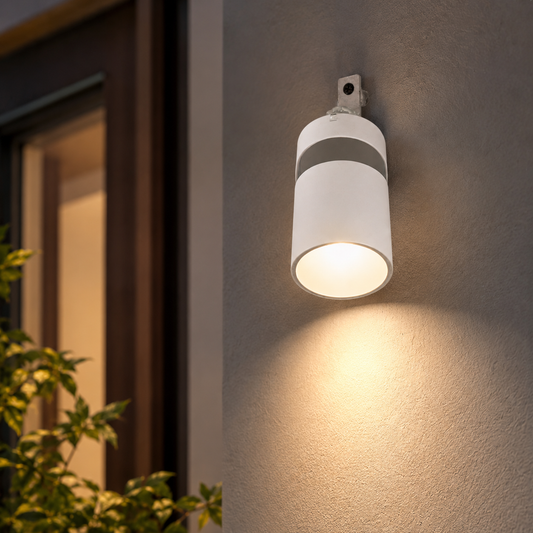 White outdoor wall light fixture on a building exterior with warm glow
