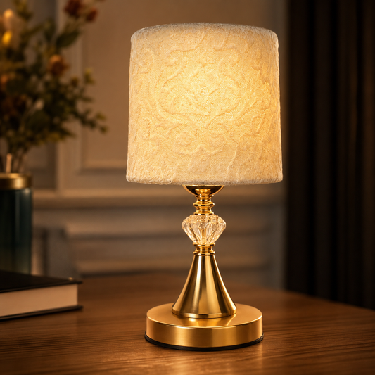 Decorative table lamp with gold base and textured white shade on a wooden surface.