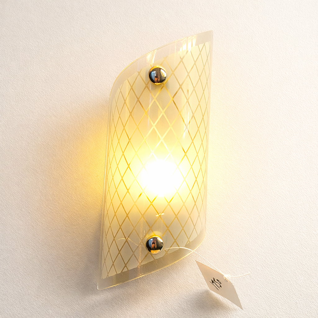 Wall-mounted light fixture with geometric design on a white wall