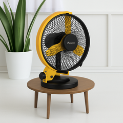 Yellow and black fan on a wooden table with a plant in the background