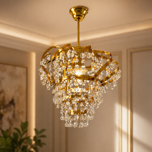 Gold chandelier with crystal accents hanging in a room with neutral walls and a plant.