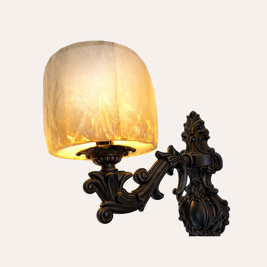 Ornate black plastic wall sconce with warm golden glow